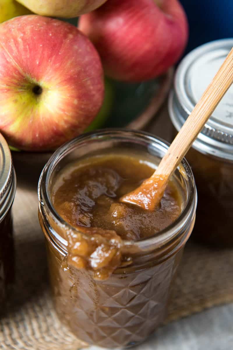 stovetop apple butter in jelly jar with small wooden spoon