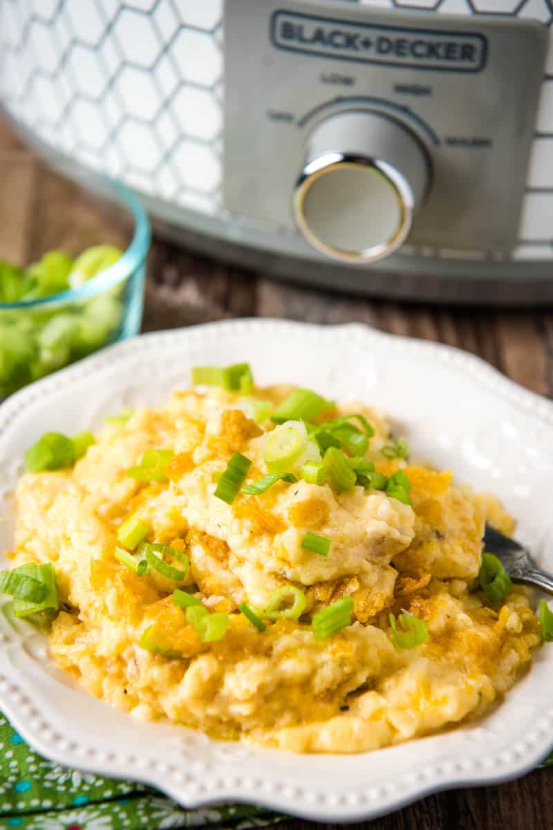 serving of CrockPot cheesy hashbrown potatoes on white plate with fork