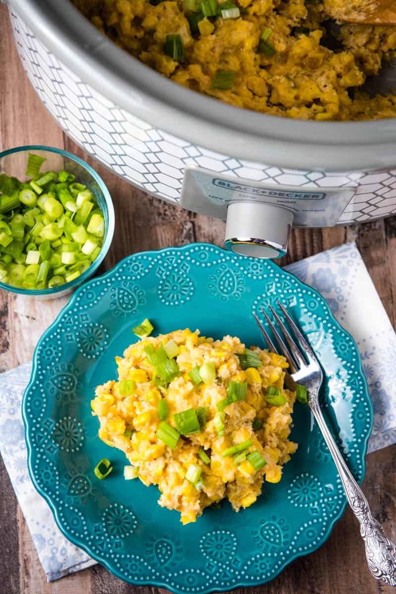 slow cooker corn pudding in slow cooker and on teal plate with fork, on wooden countertop