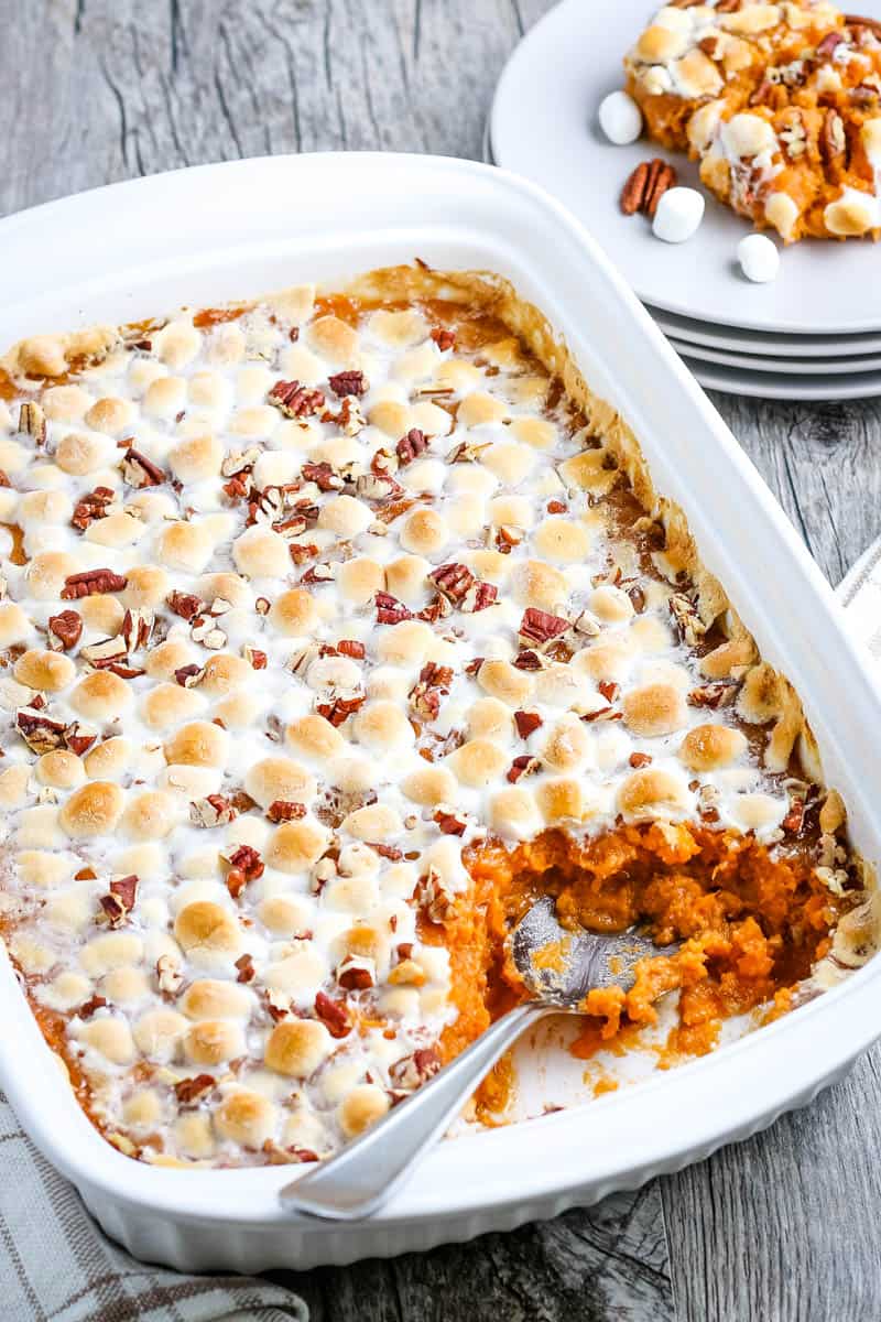 spoon in sweet potato casserole in white baking dish