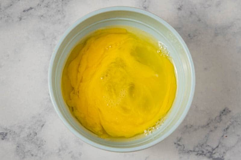 slightly beaten eggs for rolled sugar cookies in small blue bowl