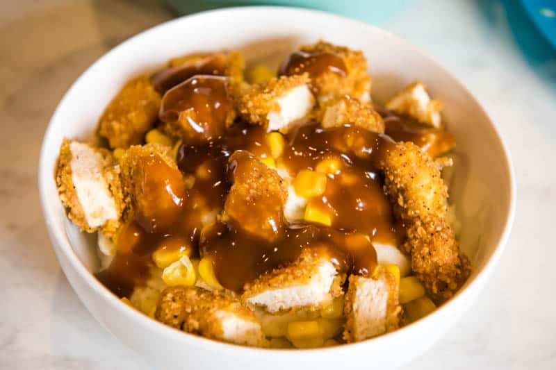 brown gravy spooned on top of KFC mashed potato bowl in white serving bowl