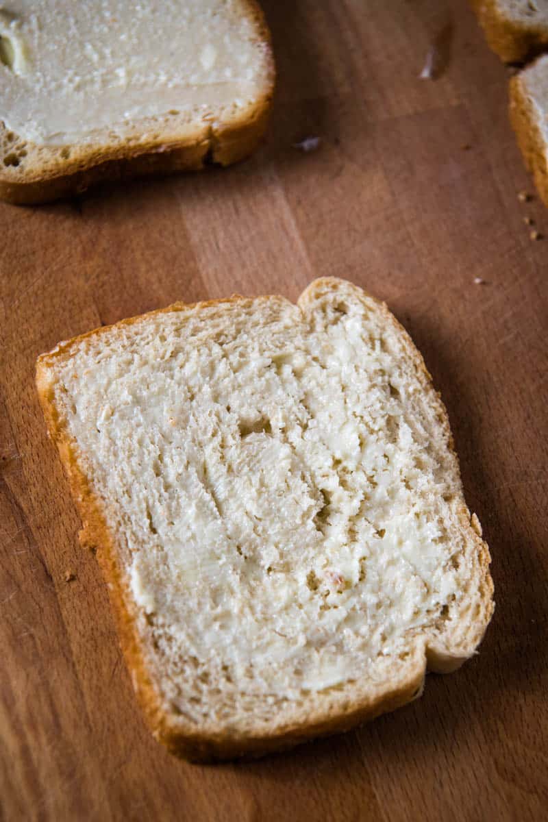 buttered slide of bread on wooden cutting board