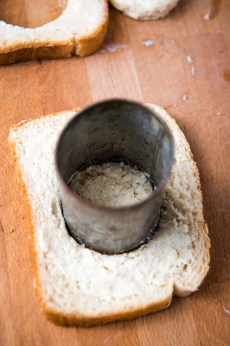 cutting a hole in center of buttered bread with small biscuit cutter (old apple juice can)