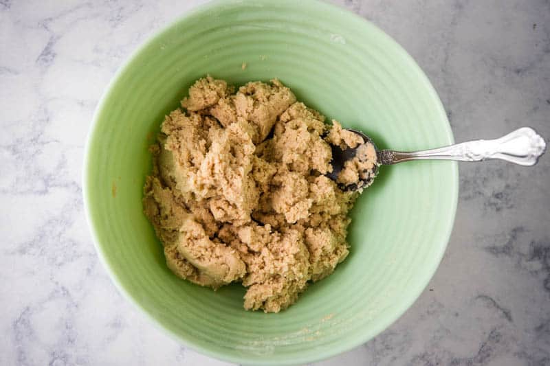 Bisquick scones dough in mint green bowl with large spoon on white marble countertop