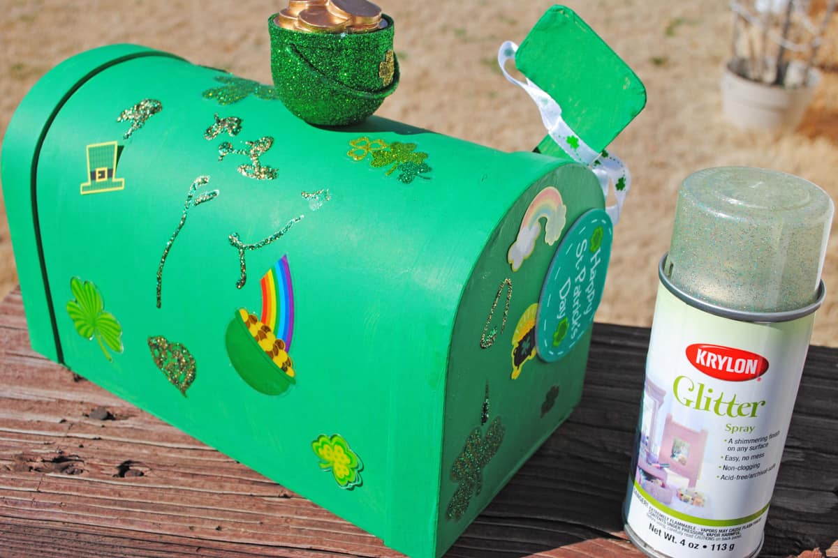 spraying Krylon glitter spray on green leprechaun box