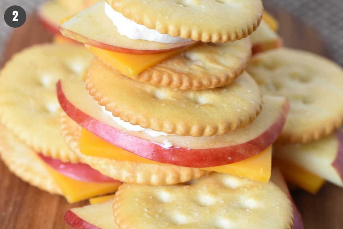 making cheese and crackers with apples stack on wooden cutting board