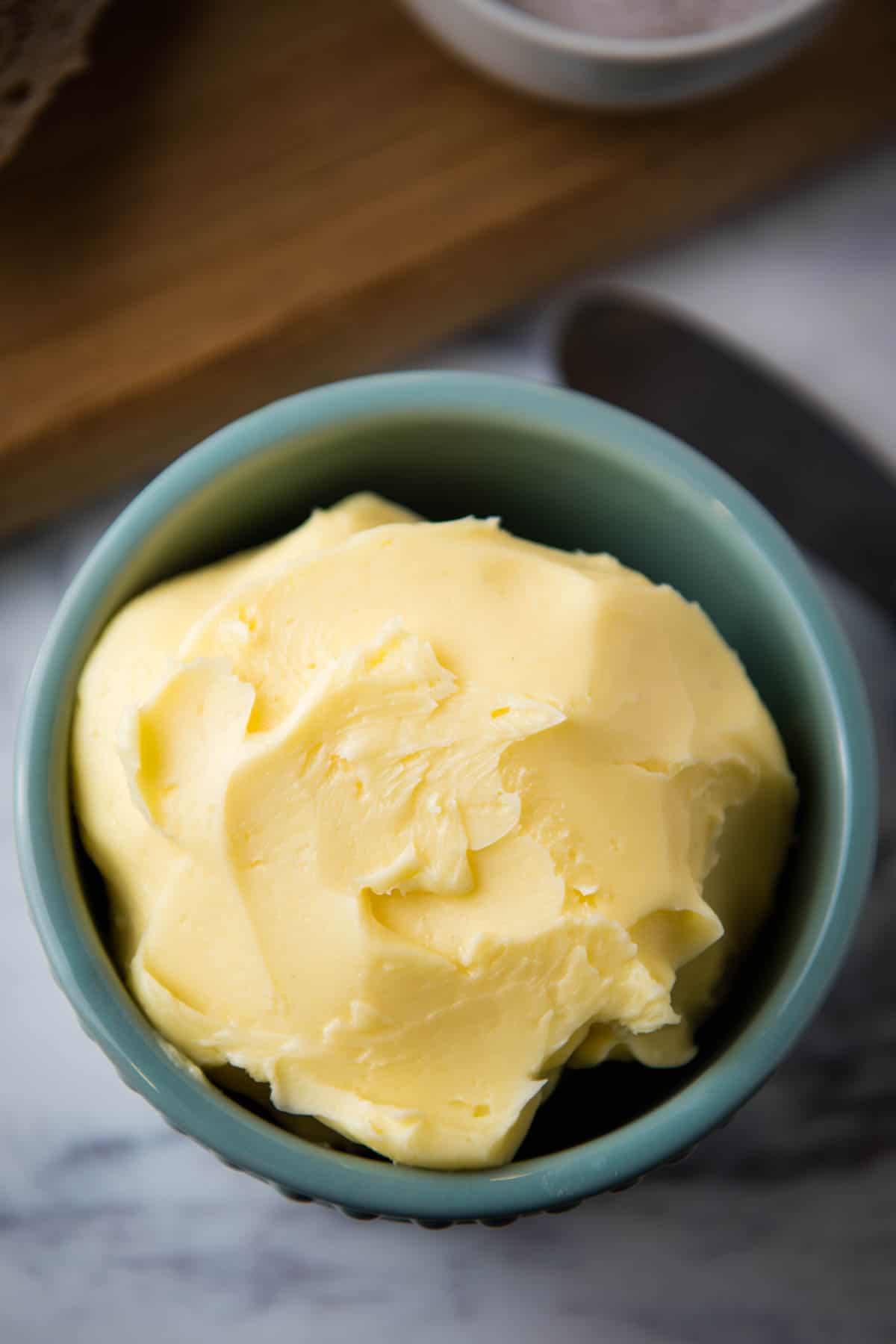 homemade salted butter from raw milk in blue ramekin on white marble countertop