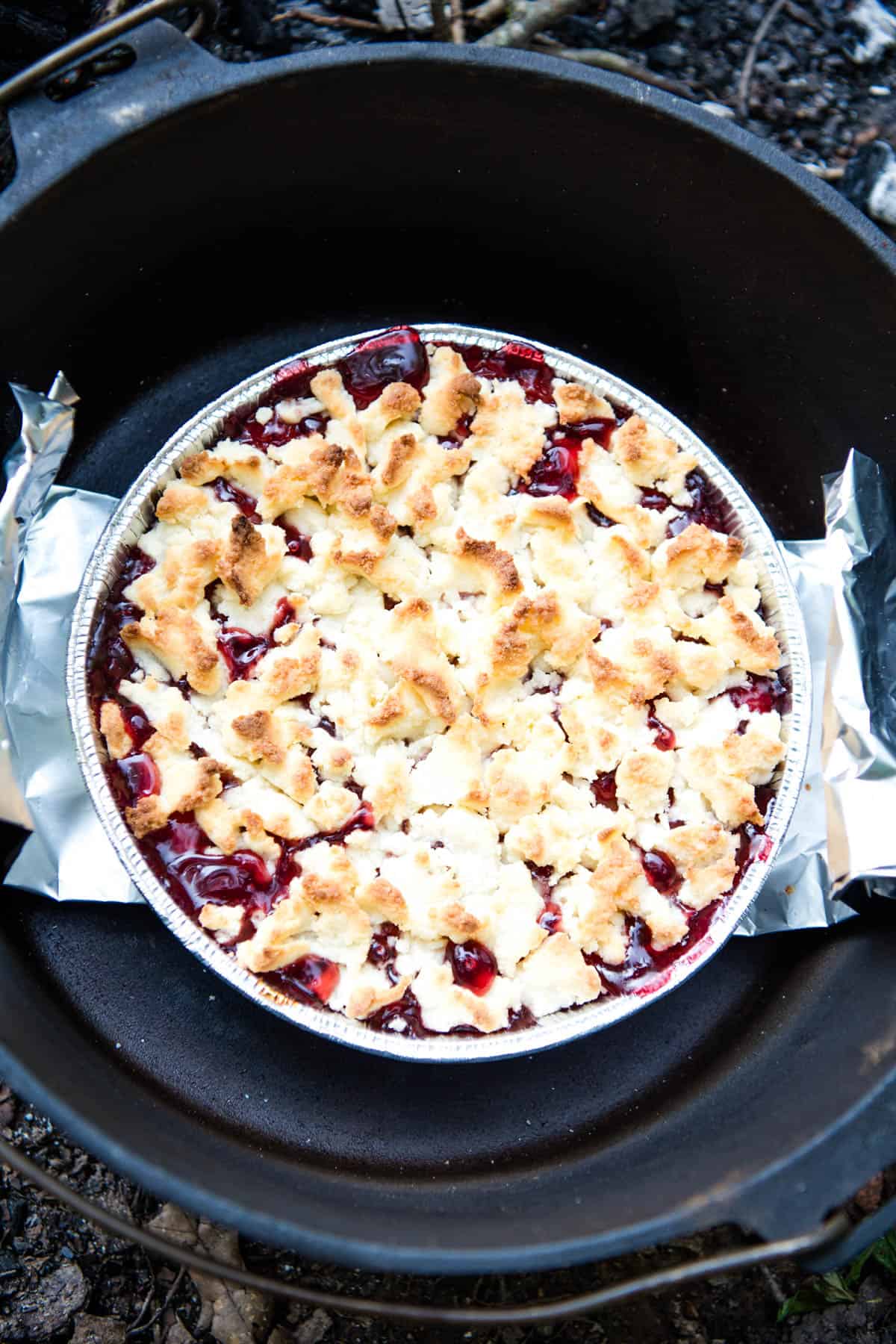 campfire cobbler in an aluminum pie plate inside of a large cast iron Dutch oven