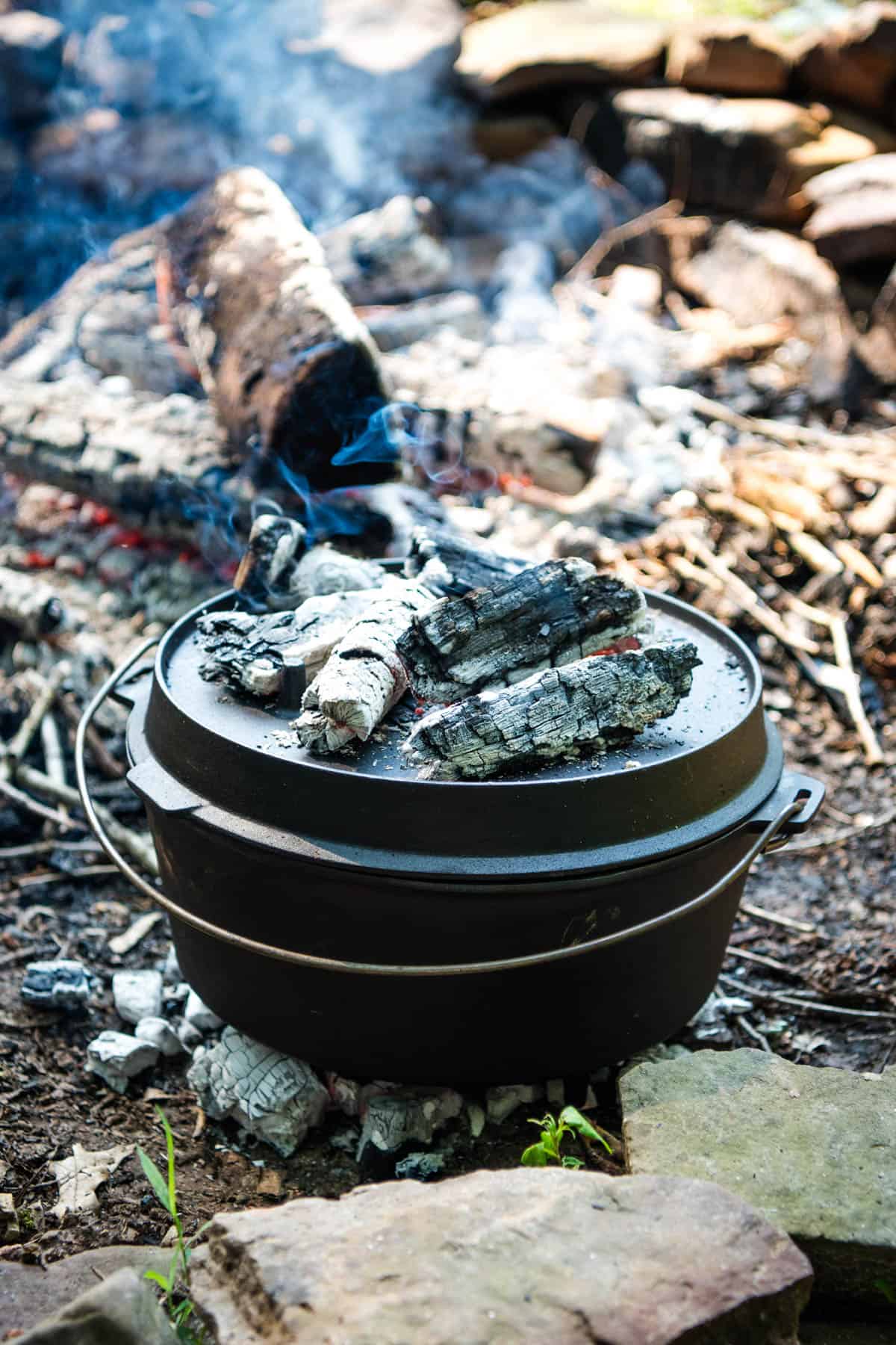 large cast iron Dutch oven on a bed of hot coals in the fire pit