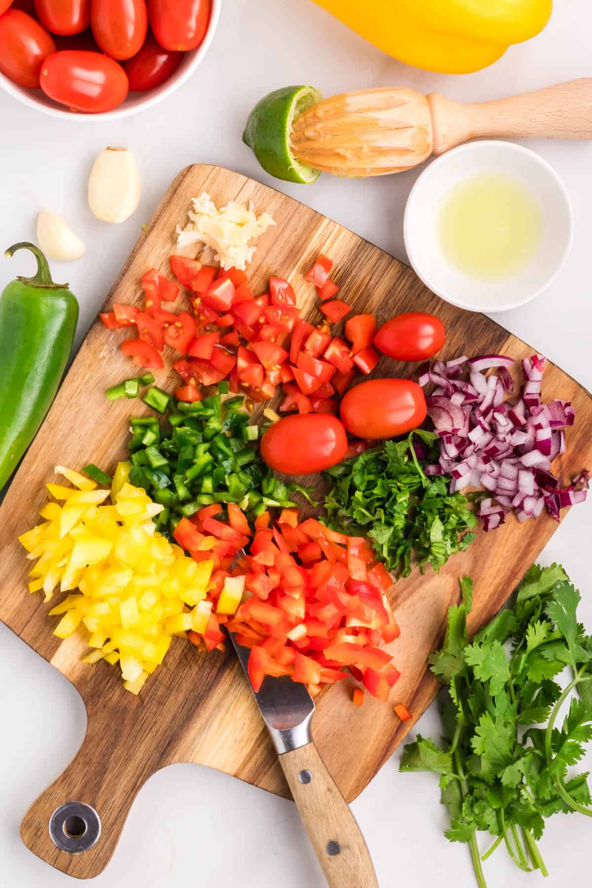 diced up fruits and veggies on a large wooden cutting board ready to make a batch of peach mango salsa