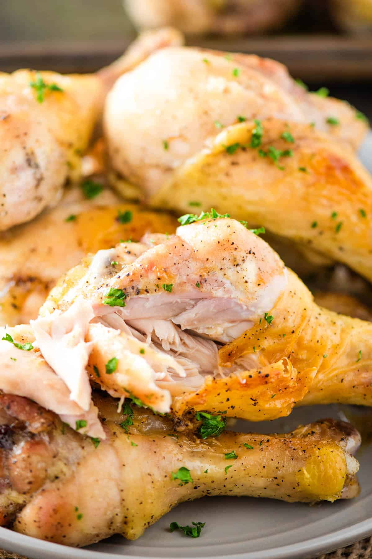 baked chicken leg with a bite taken out on a small gray plate