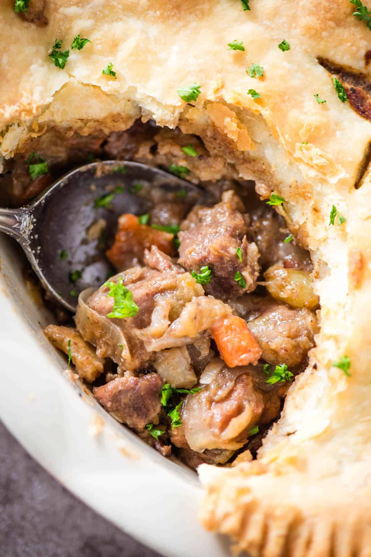 closeup photo on a large spoonful of beef pie in a large white pie plate