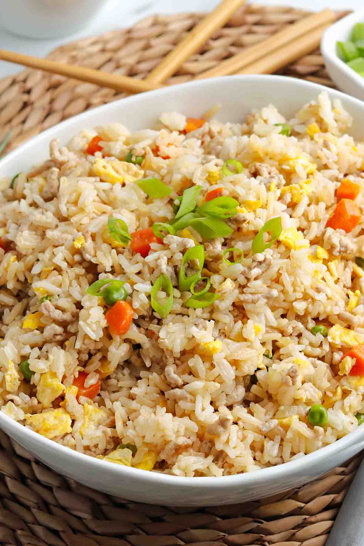 Chinese pork fried rice garnished with green onions in a small white decorative bowl