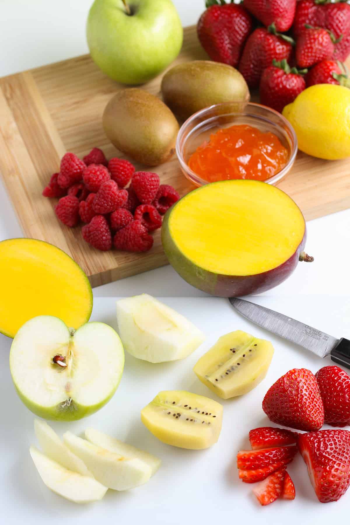 salsa recipe with fruit ingredients lined out on a large wooden cutting board with a large chef's knife